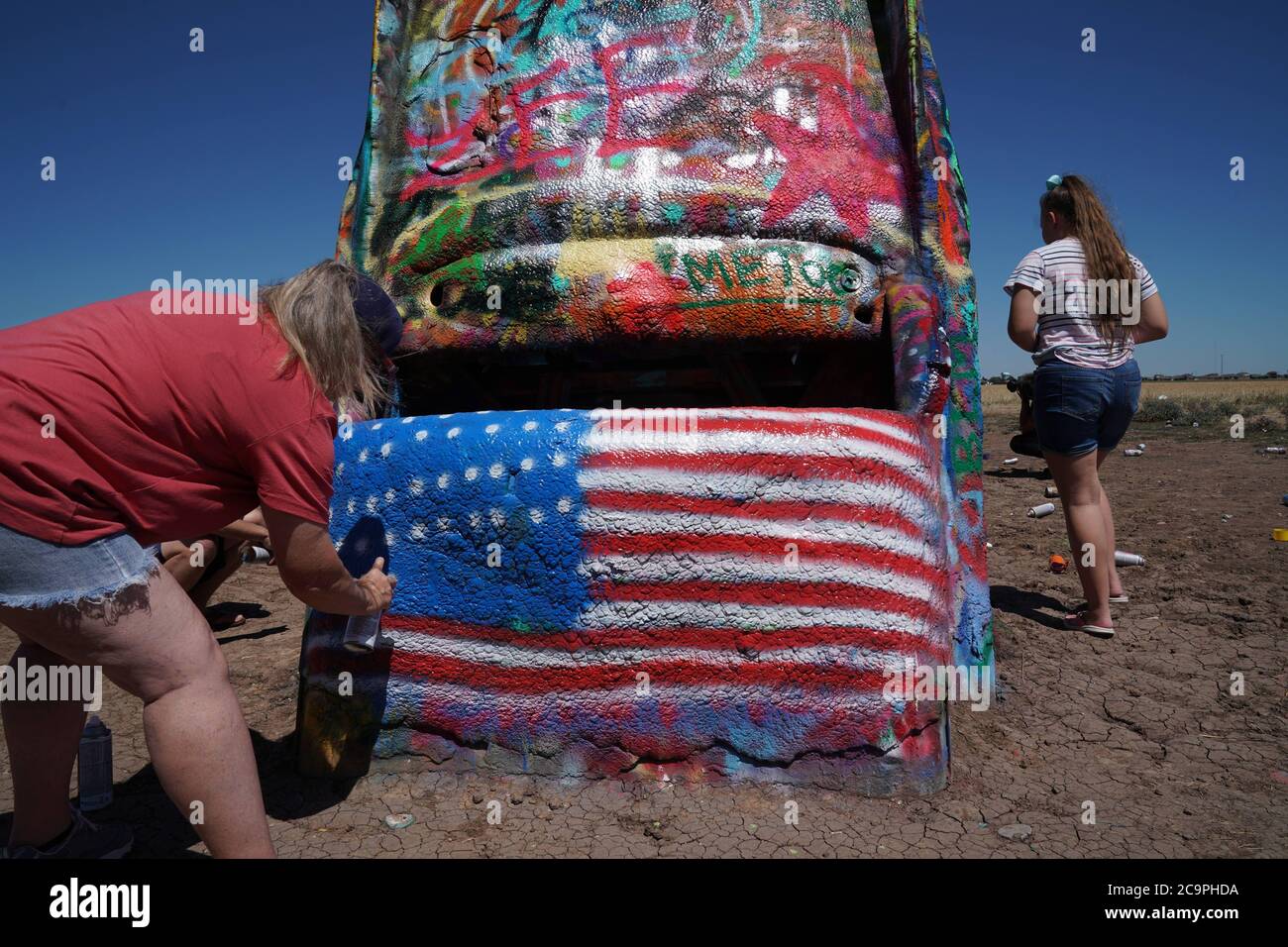 TX, États-Unis. 31 juillet 2020. Une femme en spray peint un drapeau américain au Cadillac Ranch, une installation d'art et de sculpture publique à Amarillo, Texas, le 31 juillet 2020. Il a été créé en 1974 par Chip Lord, Hudson Marquez et Doug Michels, qui faisaient partie du groupe d'art Ant Farm. L'installation se compose de dix Cadillac enterrés nez en premier dans le sol. Crédit : Bryan Smith/ZUMA Wire/Alay Live News Banque D'Images