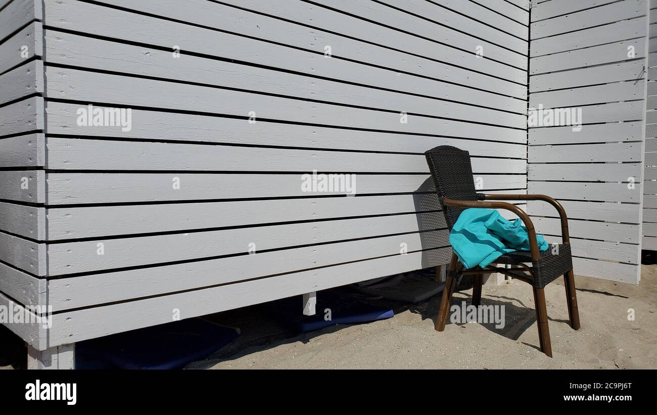 Chaise en rotin avec couverture bleue émiettée sur fond blanc peint en bois peint avec espace pour copier. Mur en bois rayé de la maison d'été de plage sur propre Banque D'Images