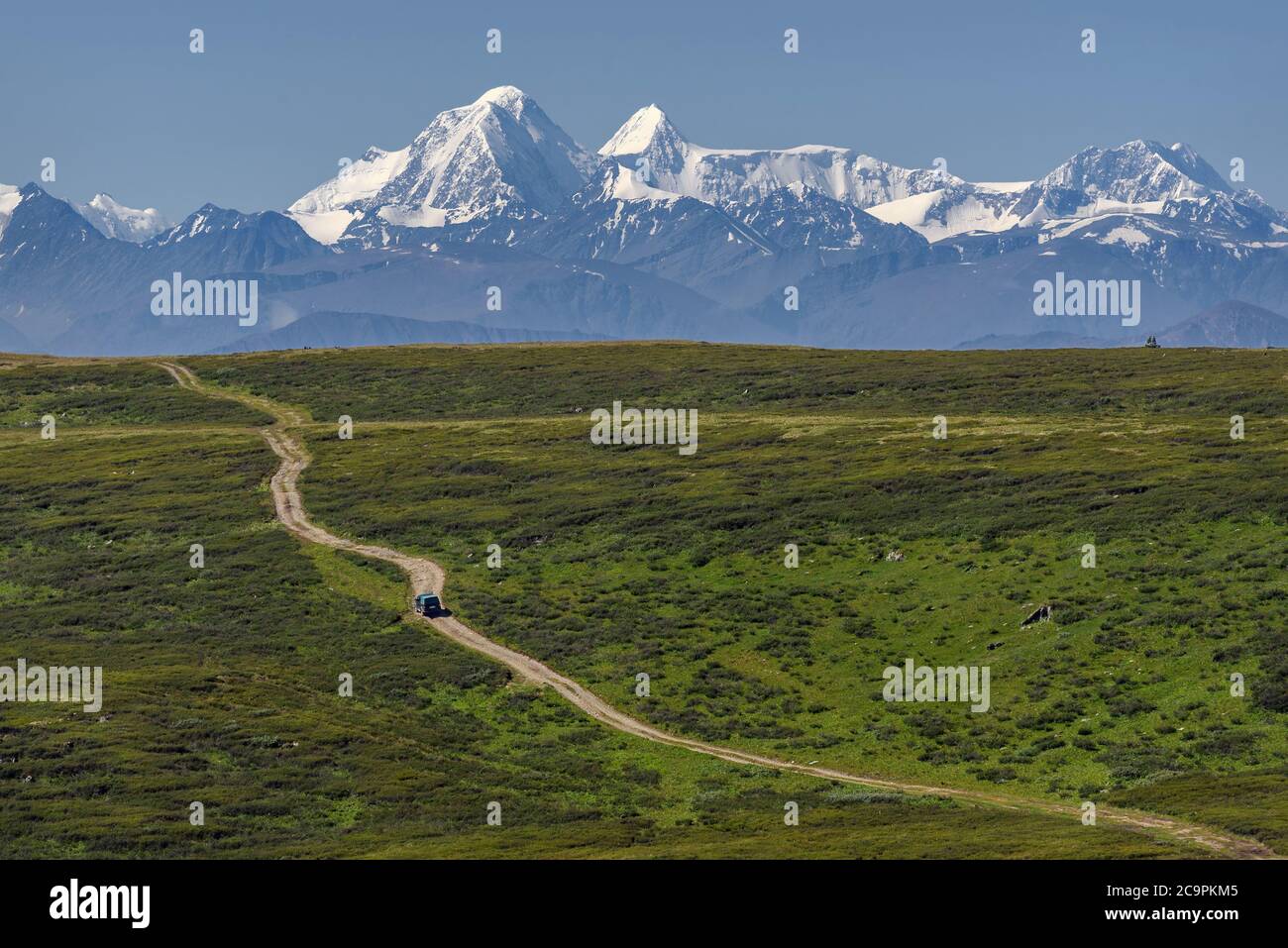 Vue incroyable avec une voiture sur une route sinueuse en terre qui longe la pente de la montagne parmi les épaissis des buissons nains de bouleau sur le fond o Banque D'Images