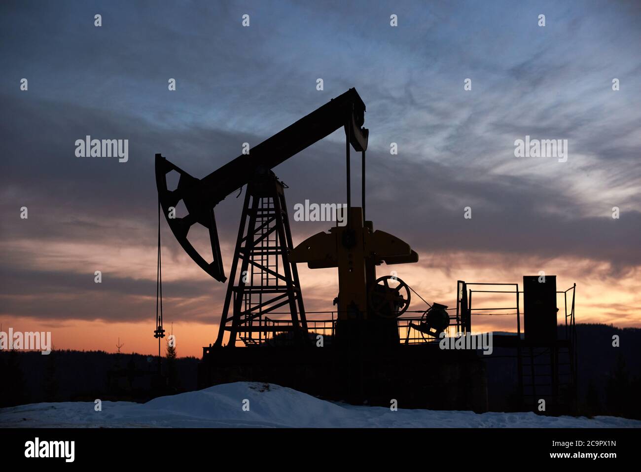 Vue du ciel spectaculaire du soir sur le vérin de pompe à pétrole à faisceau équilibré à course longue. Champ d'huile avec unité de pompage d'huile ou machine à bascule de pompe à huile pendant le coucher du soleil. Concept de l'industrie pétrolière, extraction de pétrole Banque D'Images