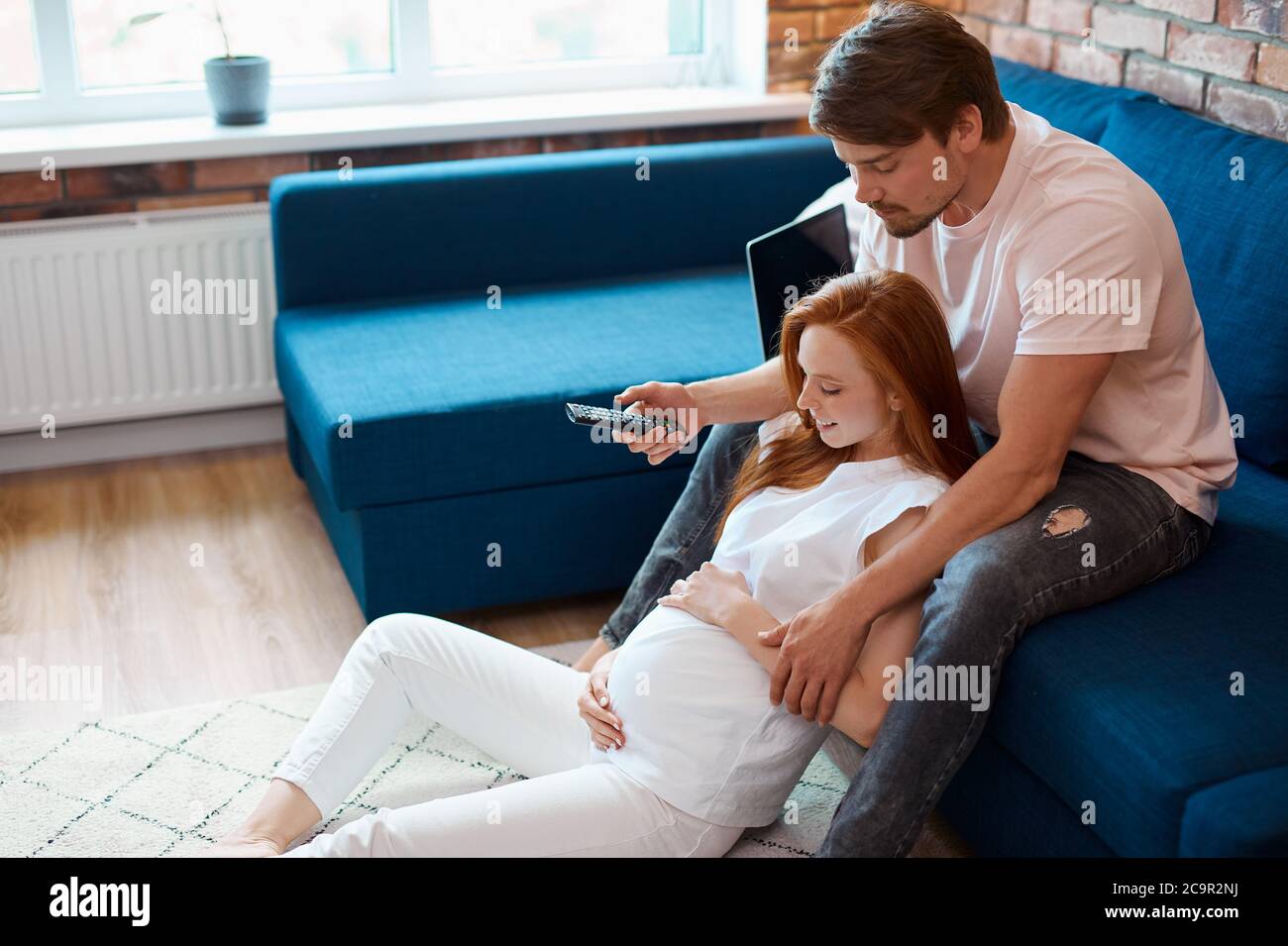 jeune couple marié regarder la télévision ensemble à la maison, femme  enceinte redhead et beau gars aiment le repos Photo Stock - Alamy