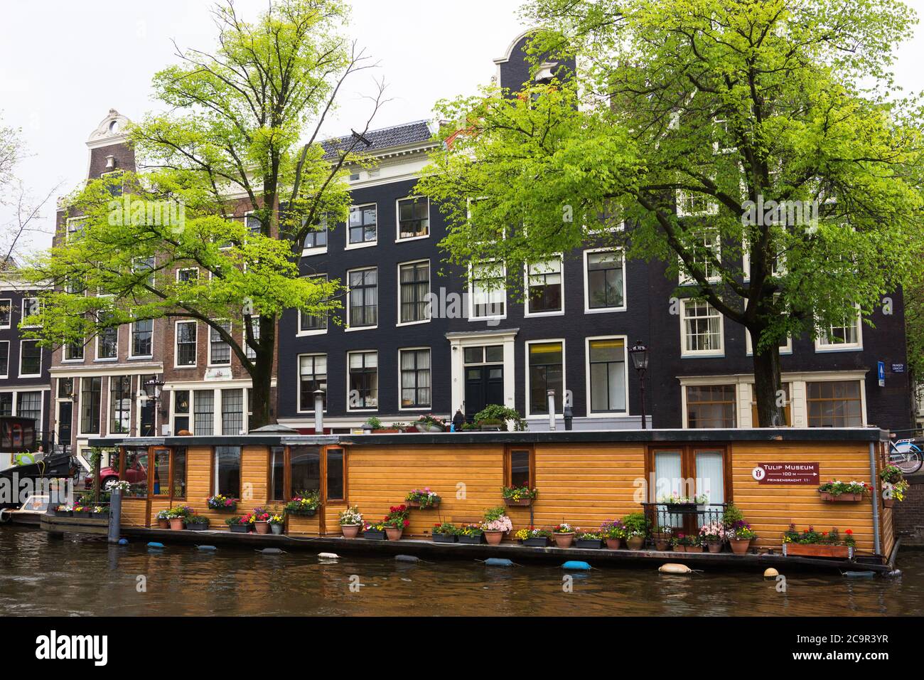 Bateau maison dans le canal d'Amsterdam en face de belles maisons uniques d'Amsterdam, pays-Bas Banque D'Images