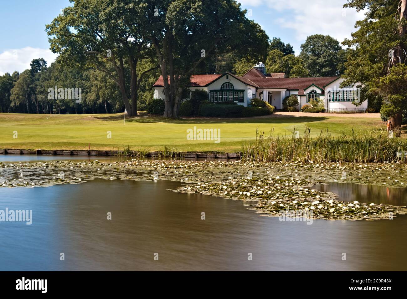 Woking Golf Club House avec vue sur l'étang soyeux herbe fraîchement coupée et ciel d'été lumineux Banque D'Images