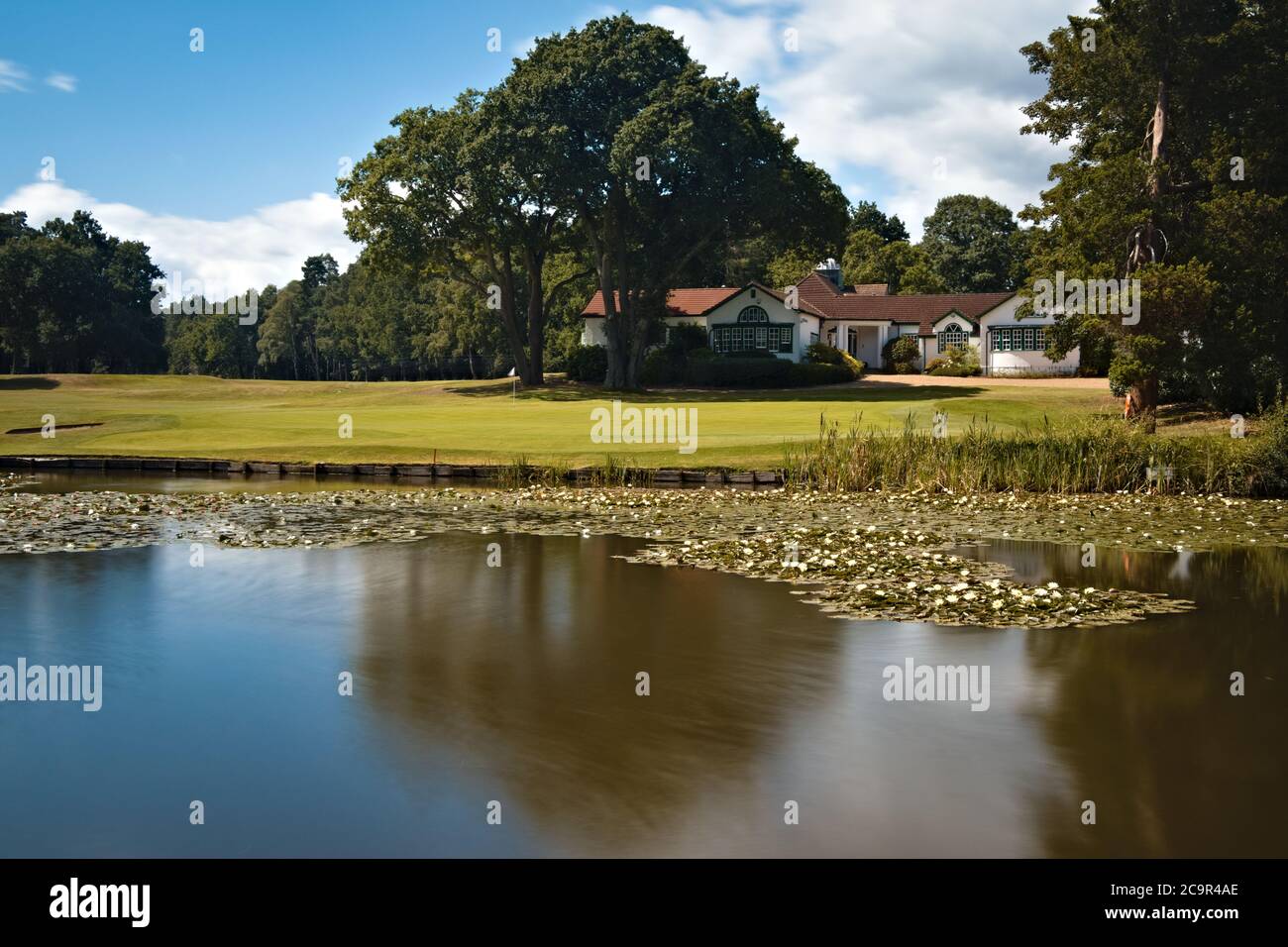 Woking Golf Club House avec vue sur l'étang soyeux herbe fraîchement coupée et ciel d'été lumineux Banque D'Images