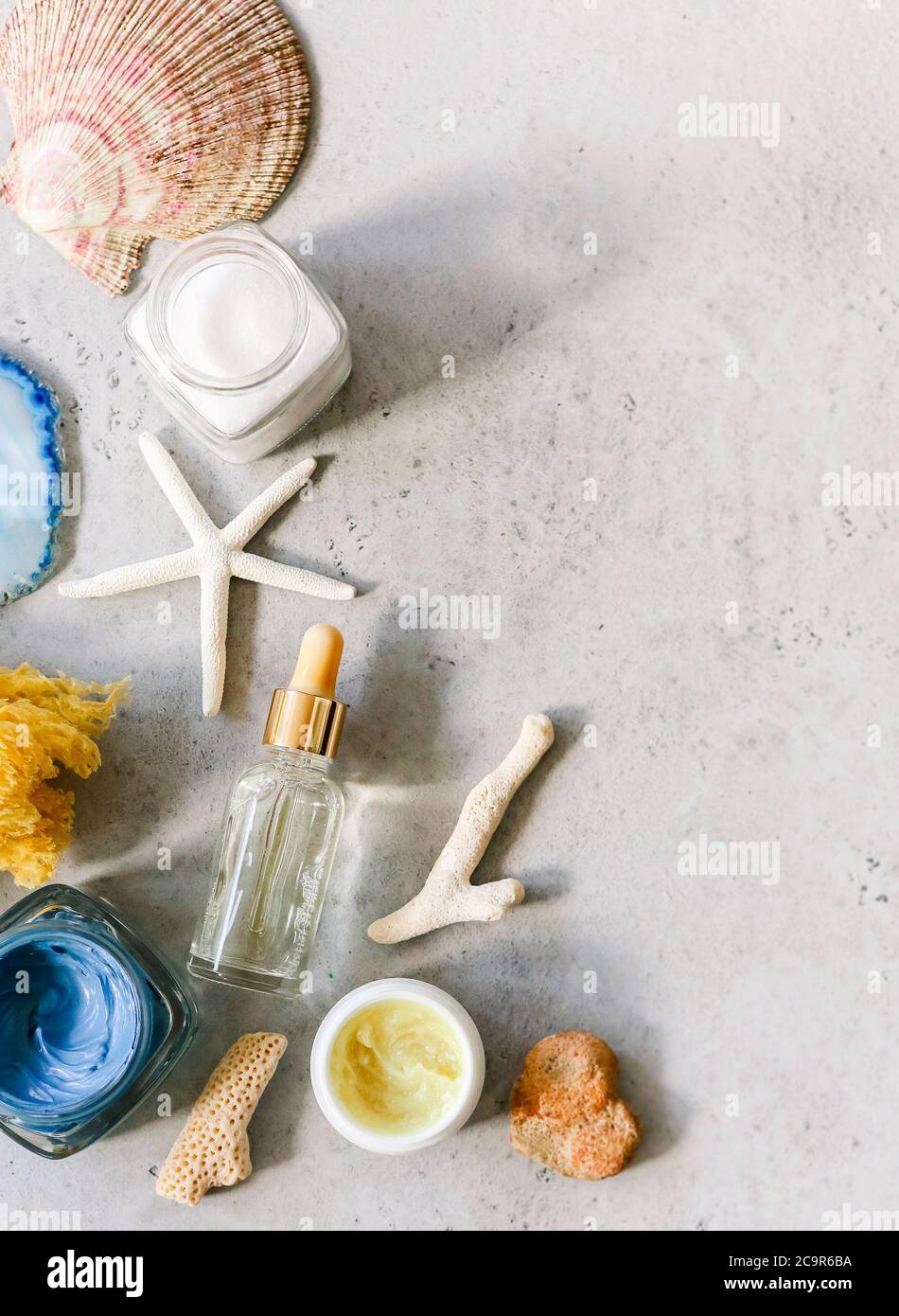 Vue de dessus de divers produits cosmétiques dans des pots disposés sur une table avec des coquillages et de la pierre minérale Banque D'Images