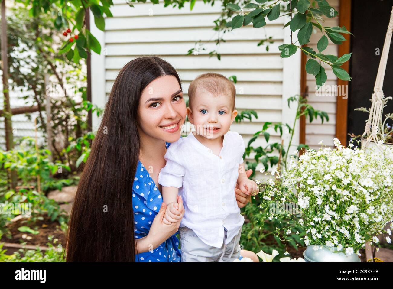 Content femme avec un petit enfant mignon se détendre dans le jardin tout en passant un week-end à la campagne Banque D'Images