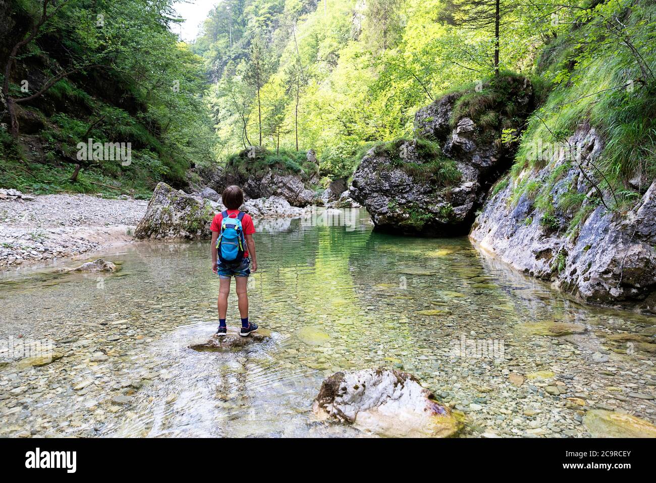 Jeune garçon debout sur un rocher lors d'une promenade en rivière Banque D'Images