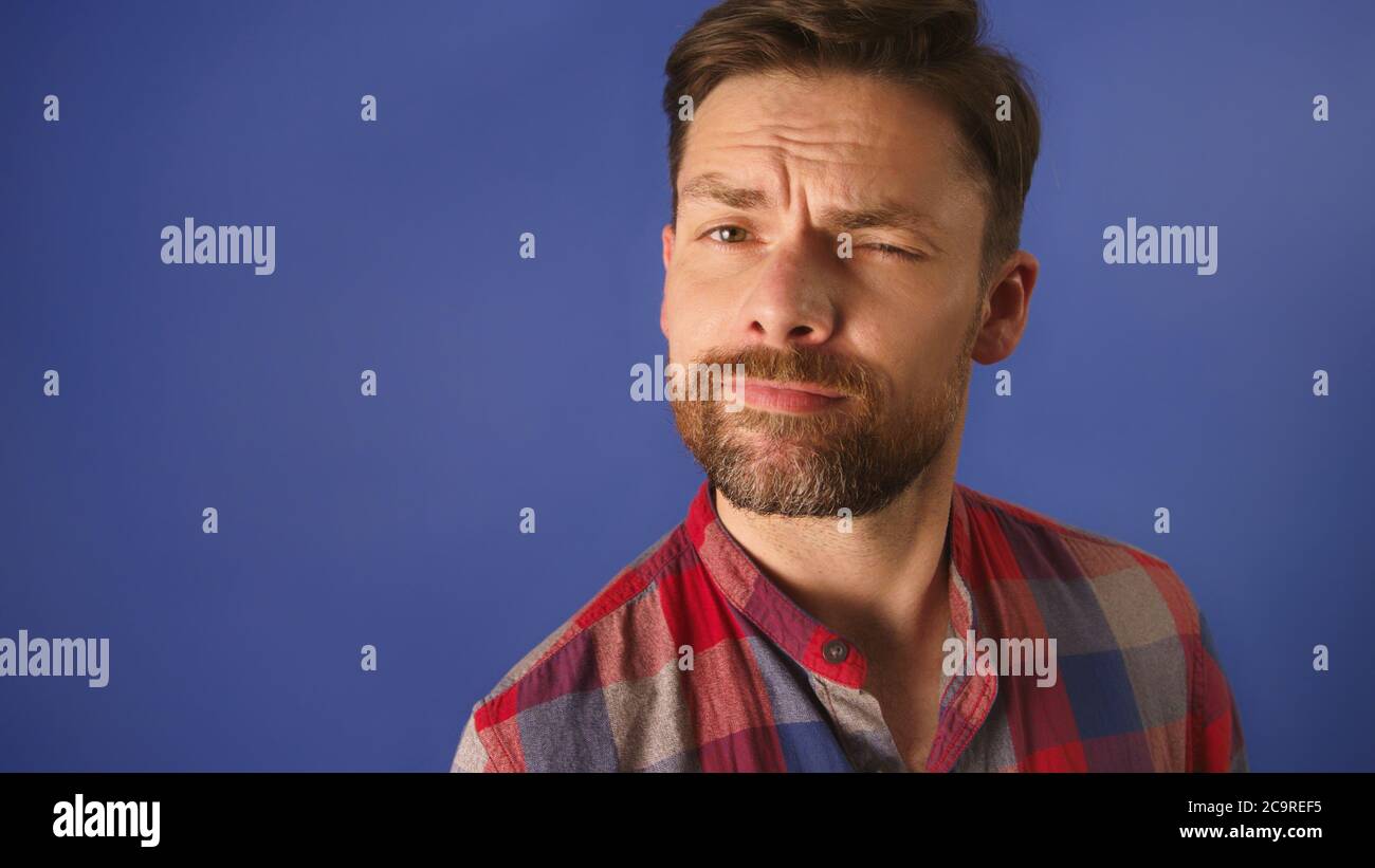 Souriant barbu jeune homme modèle, habillé à la légère, soulevant le sourcil. Copier l'espace. Photo de haute qualité Banque D'Images