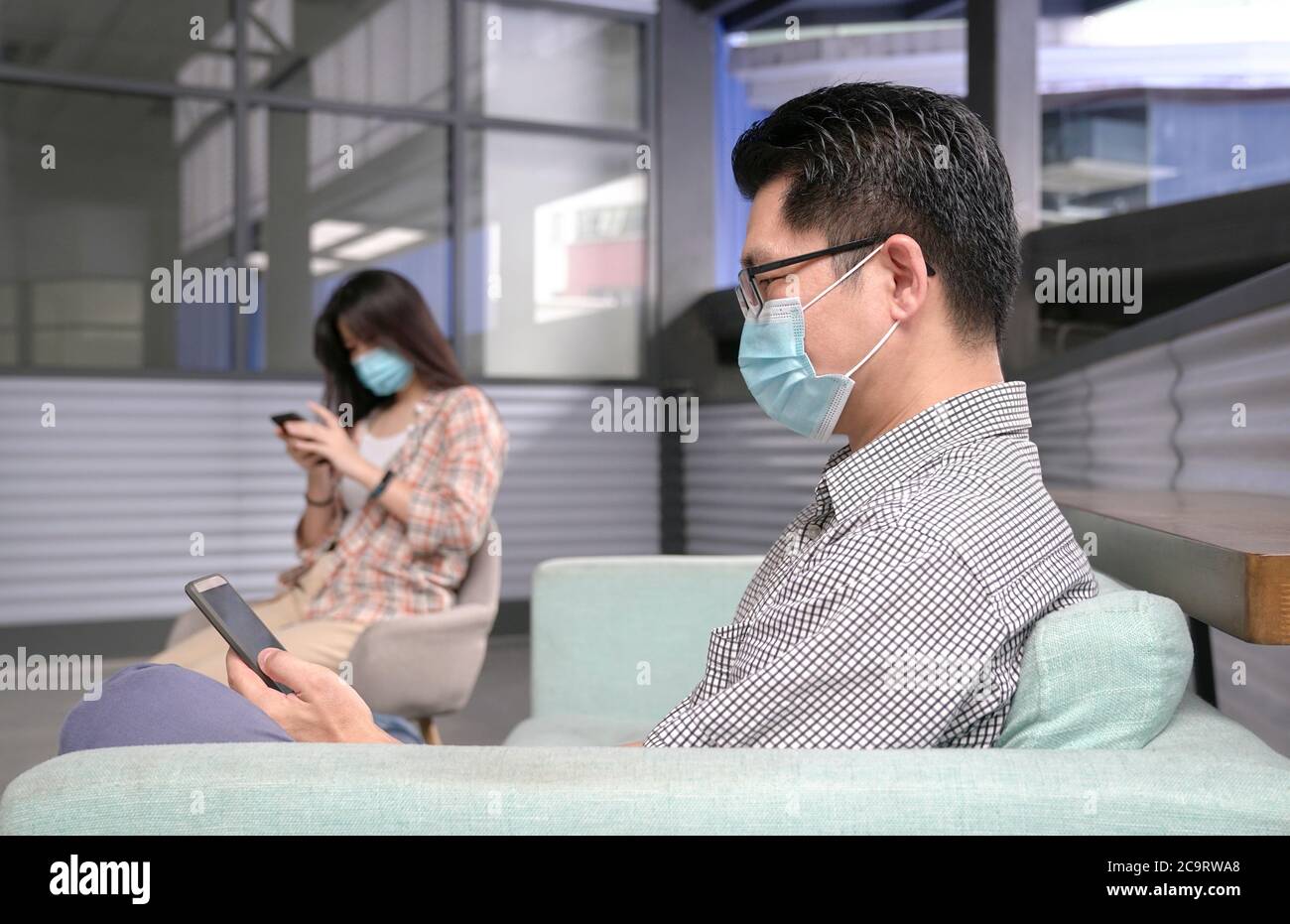 Homme et femme portant un masque de visage assis les uns à l'autre. Distanciation sociale. Protection contre Covid-19. Banque D'Images