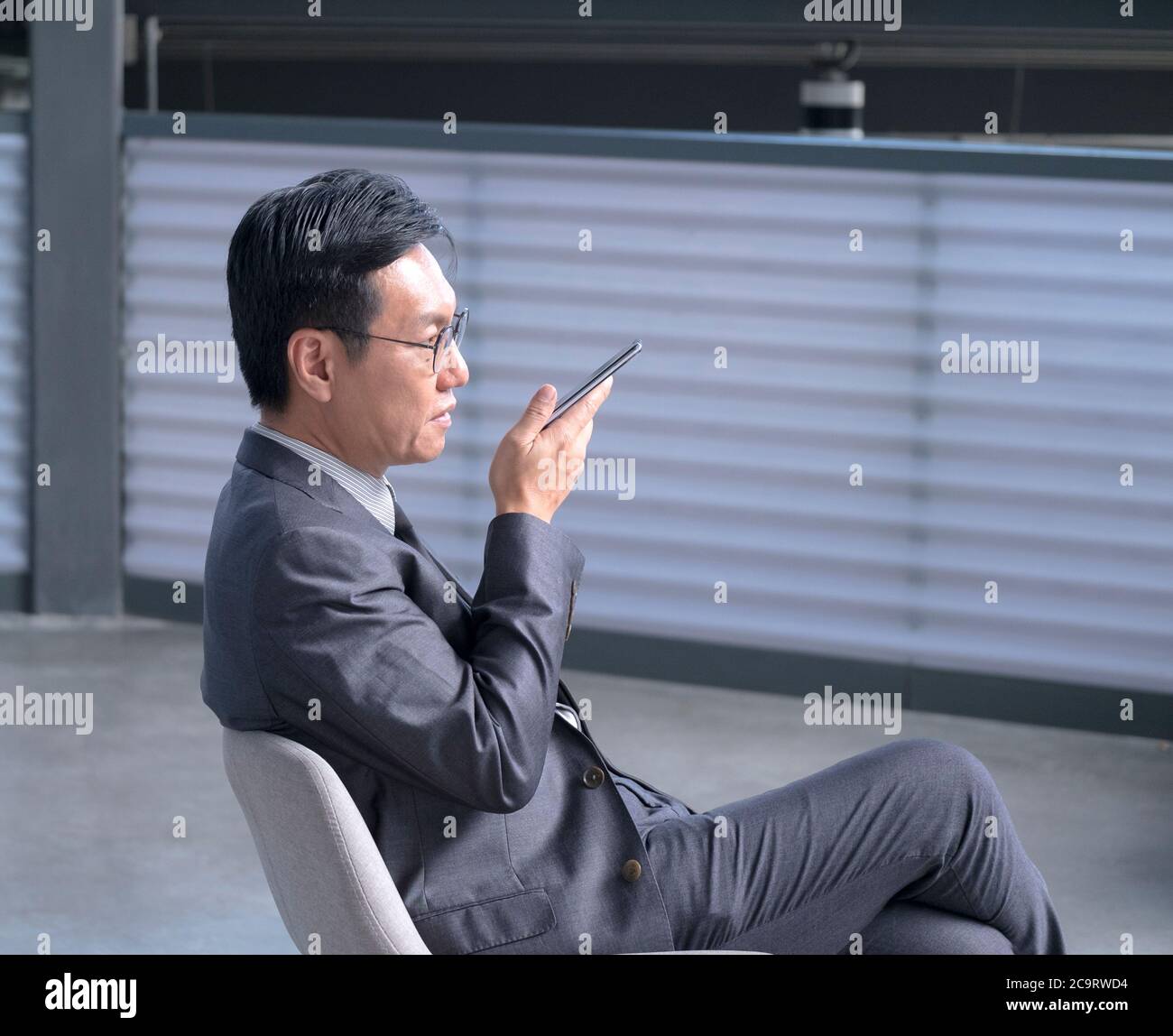 Homme d'affaires chinois utilisant un téléphone portable pour laisser un message vocal. Copier l'espace. Banque D'Images