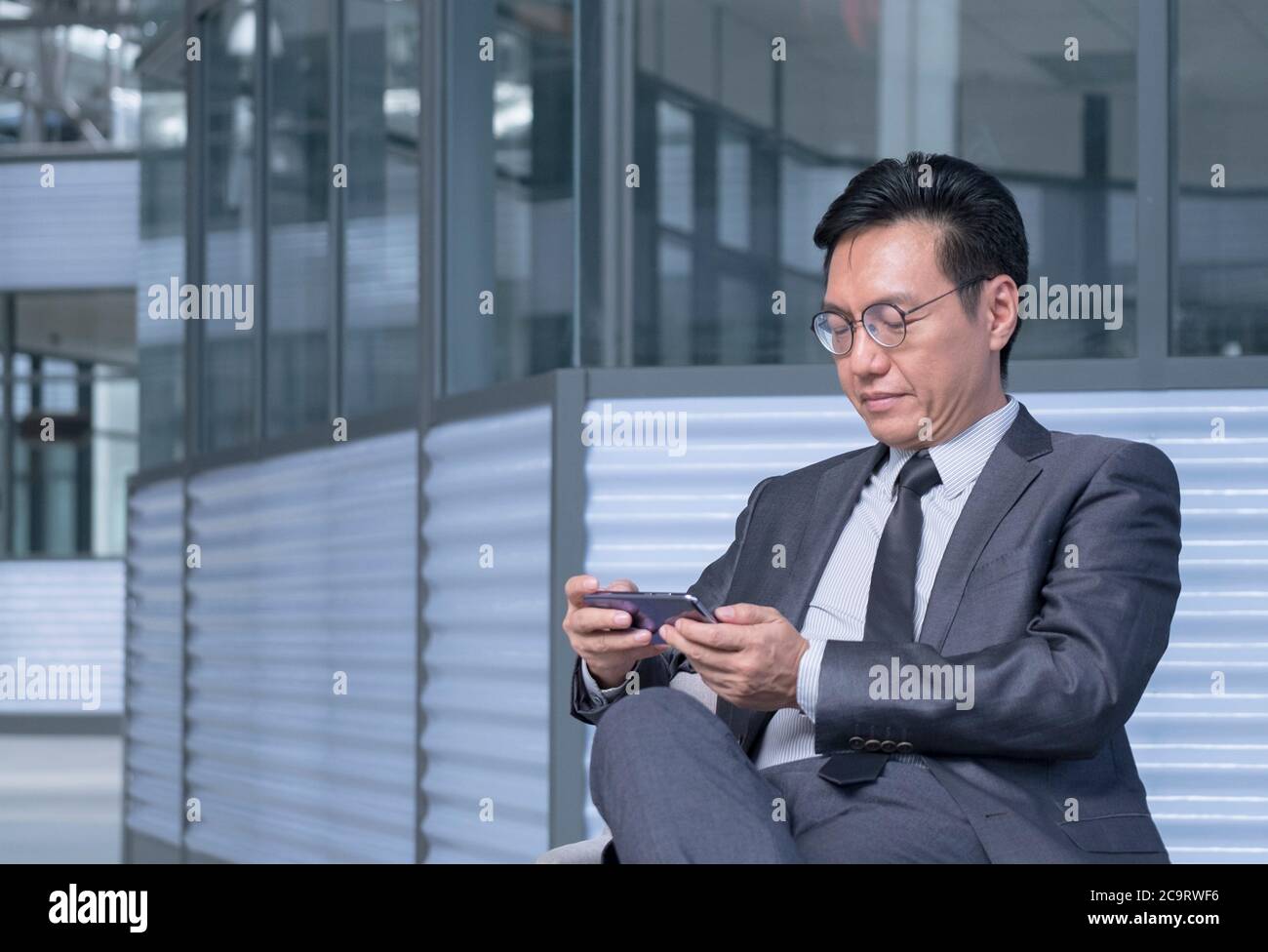 Homme d'affaires chinois en costume et cravate utilisant le téléphone  portable pour regarder en direct streaming ou vidéo Photo Stock - Alamy