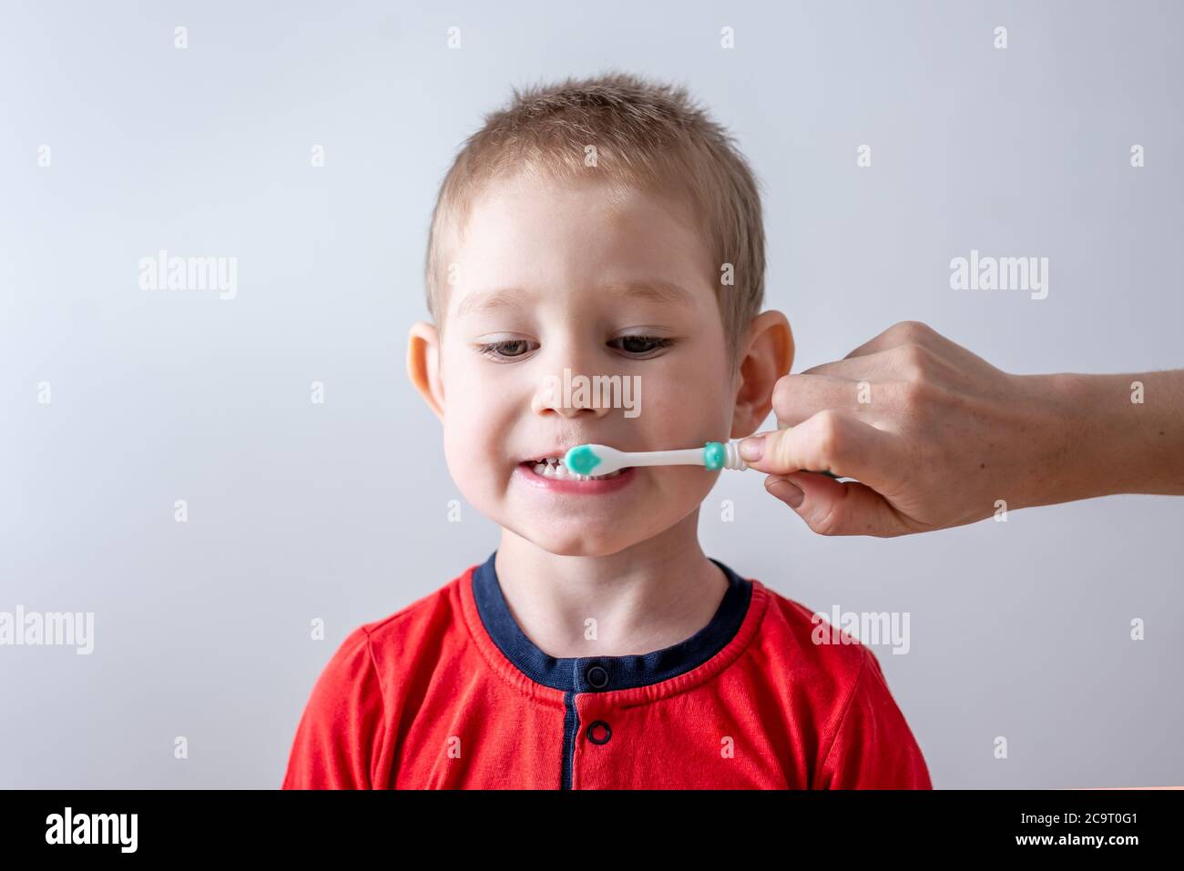 Le tout-petit se brosse les dents avec l'aide d'un parent. Concept d'apprentissage des soins dentaires et de l'hygiène pour les enfants. Banque D'Images