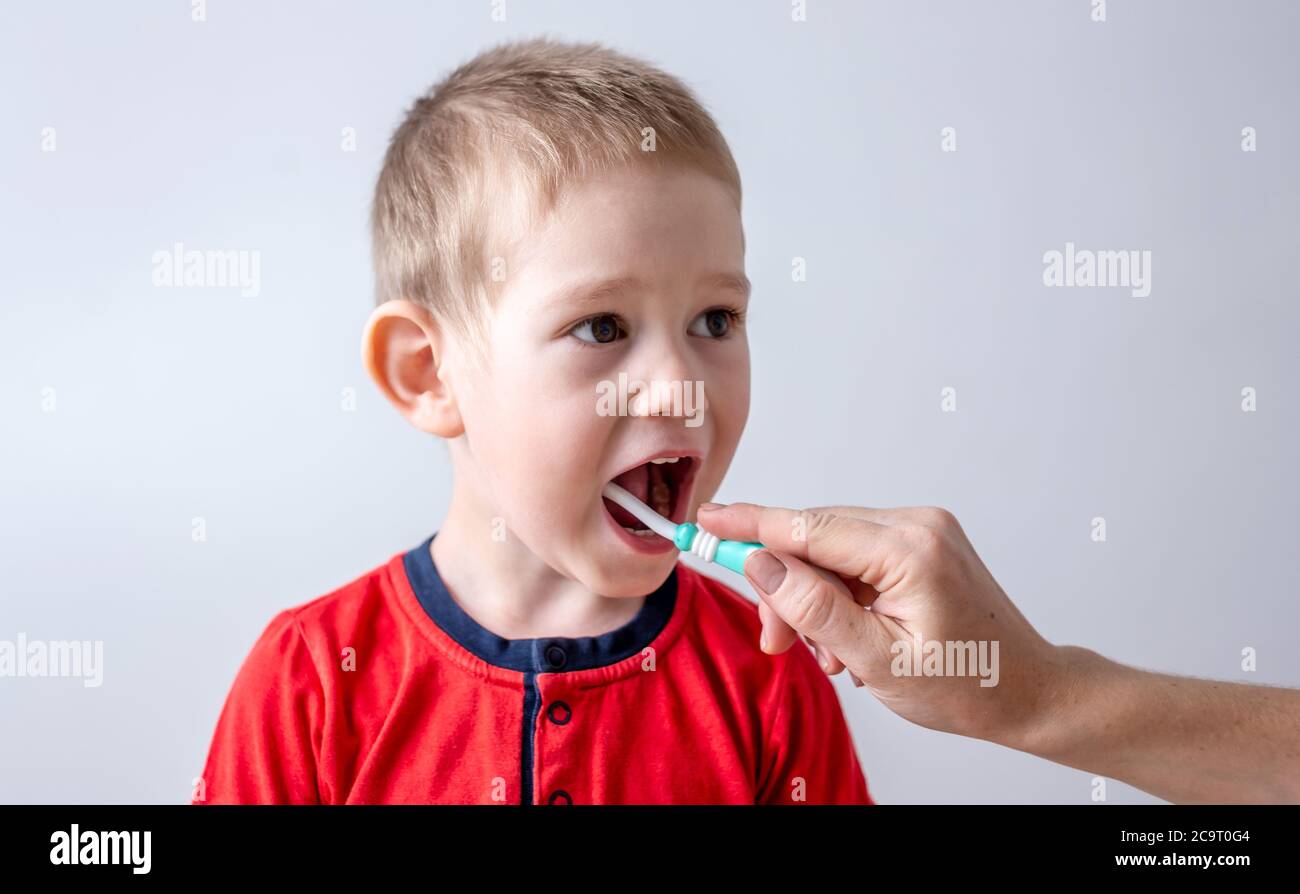 Le tout-petit se brosse les dents avec l'aide d'un parent. Concept d'apprentissage des soins dentaires et de l'hygiène pour les enfants. Banque D'Images