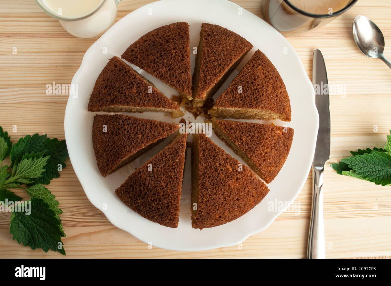 Tranché, divisé tarte éponge en sable portionsand et une tasse de café avec du lait sur un fond en bois. Pose à plat. Minimaliste. Banque D'Images