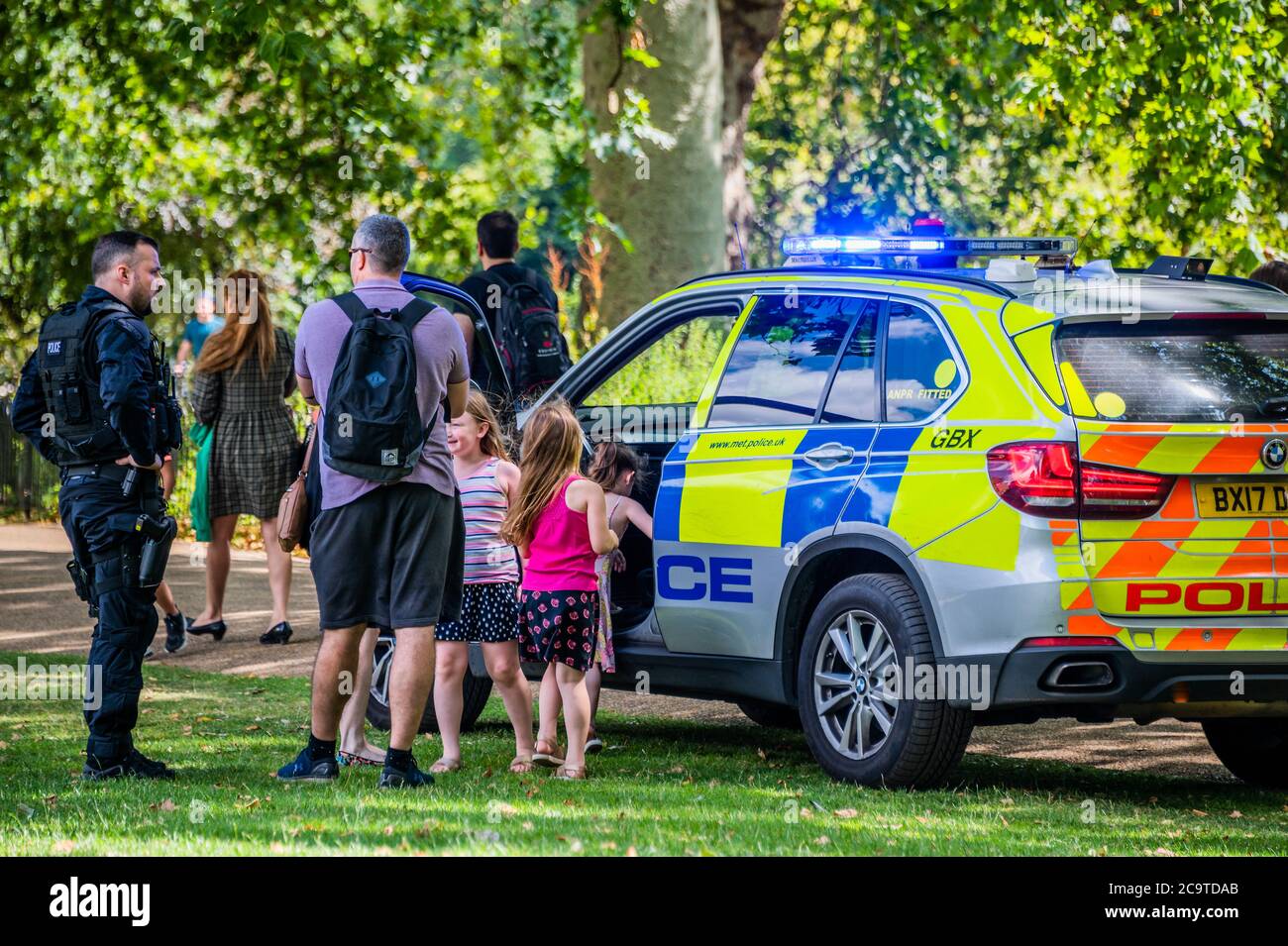 Londres, Royaume-Uni. 02 août 2020. Une unité de police armée fait un arrêt de bonne volonté après que des enfants se soient défertés à leur passage dans le parc St James. Ils s'arrêtent, les laissent grimper dans la voiture et leur donnent des autocollants. Dans ce monde covid19, ils manquent cependant des masques et de la distance sociale, mais il est possible que le père soit un collègue. Crédit : Guy Bell/Alay Live News Banque D'Images