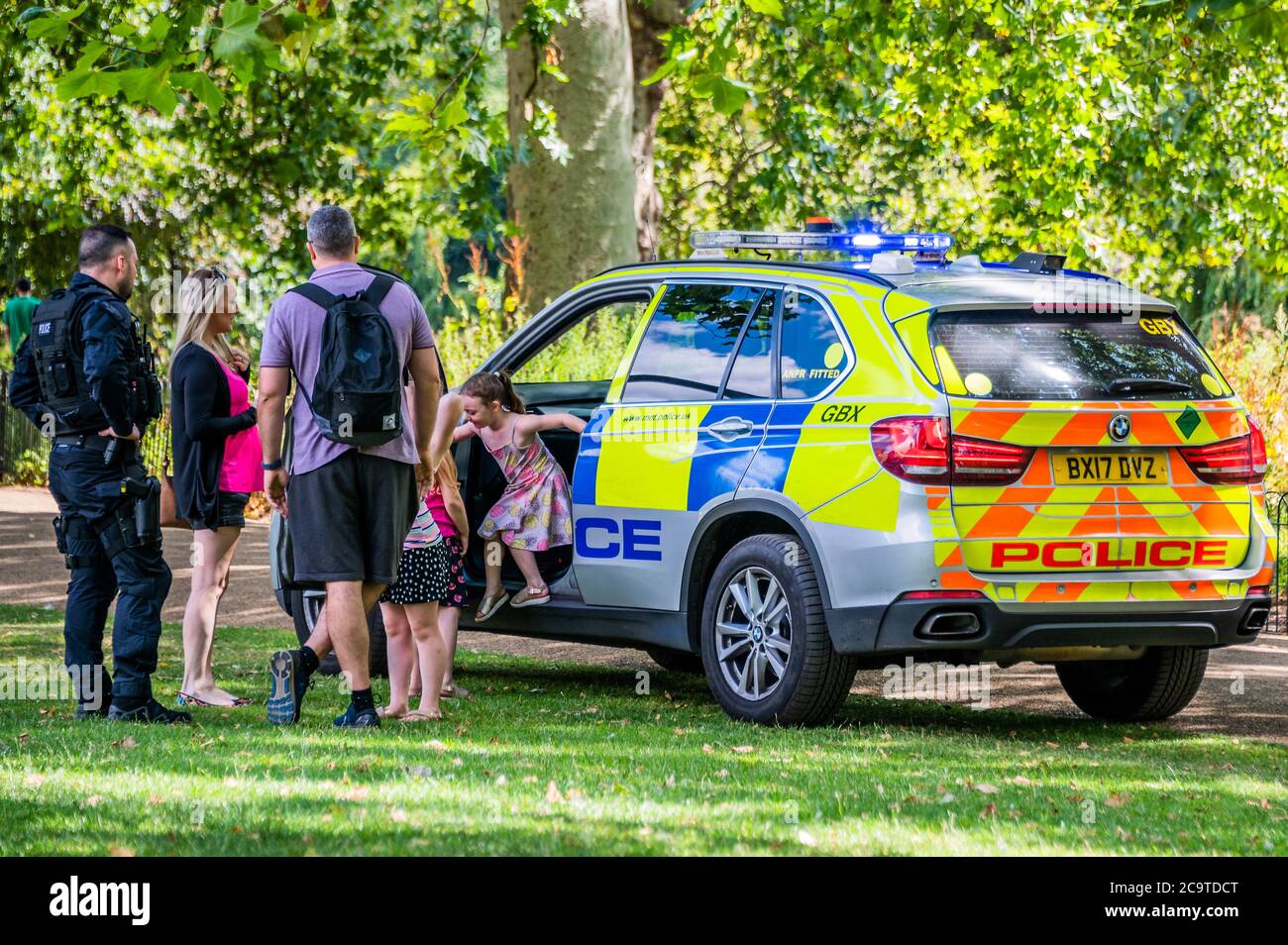 Londres, Royaume-Uni. 02 août 2020. Une unité de police armée fait un arrêt de bonne volonté après que des enfants se soient défertés à leur passage dans le parc St James. Ils s'arrêtent, les laissent grimper dans la voiture et leur donnent des autocollants. Dans ce monde covid19, ils manquent cependant des masques et de la distance sociale, mais il est possible que le père soit un collègue. Crédit : Guy Bell/Alay Live News Banque D'Images