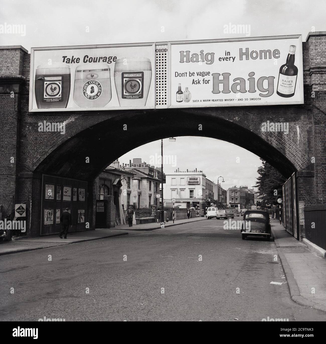 Années 1960, historique, Panneaux publicitaires ou affiches pour les marques de boissons connues de l'époque, courage Beer et Haigh Whisky sur un pont ferroviaire à la ville de Kentish, Londres, Angleterre, Royaume-Uni. Le Moretown Arms, un pub Ind Cooper vendant le Double Diamond, est visible au loin. Banque D'Images