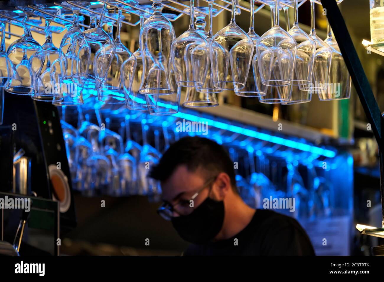 Barman flou avec masque facial dans un bar ouvert la nuit Banque D'Images