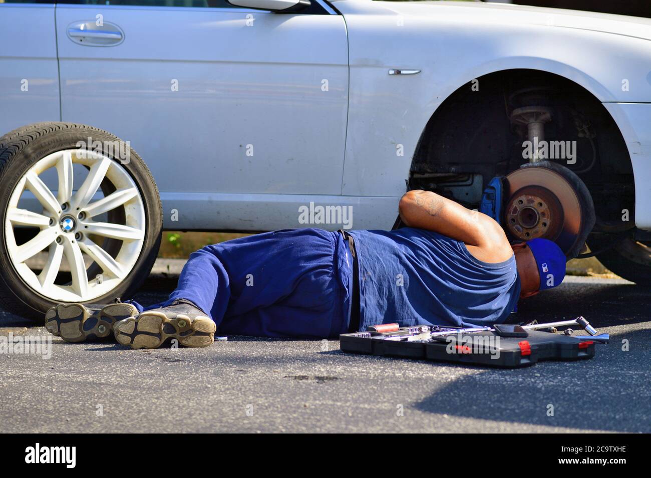 Franklin Park, Illinois, États-Unis. Lorsqu'il est prolongé sur le trottoir, un homme travaille pour terminer un travail de pause sur un véhicule dans la banlieue de Chicago. Banque D'Images