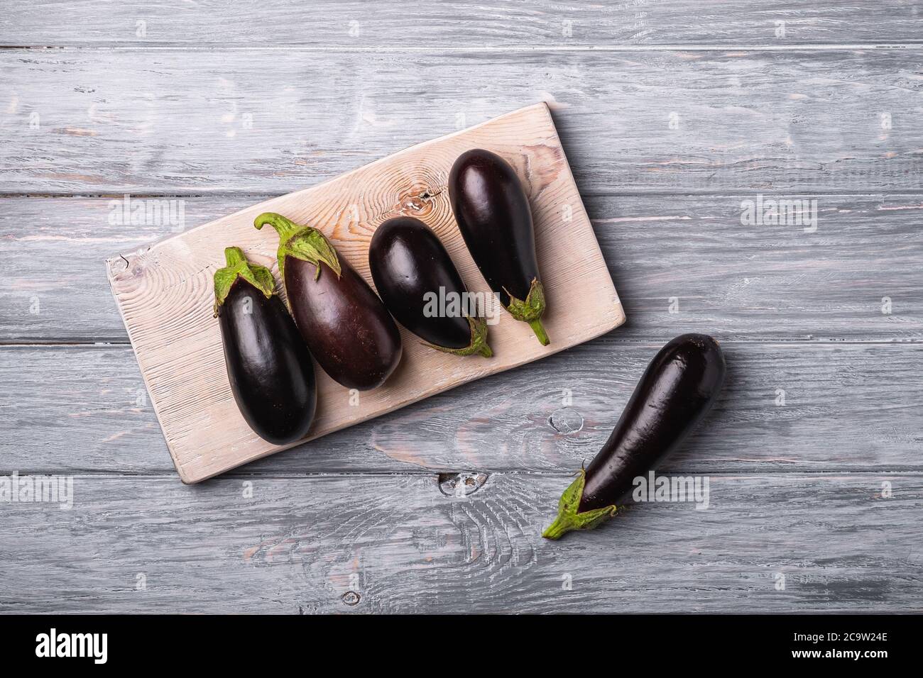 Aubergine fraîche et mûre sur planche à découper en bois, fond en bois gris, vue du dessus Banque D'Images