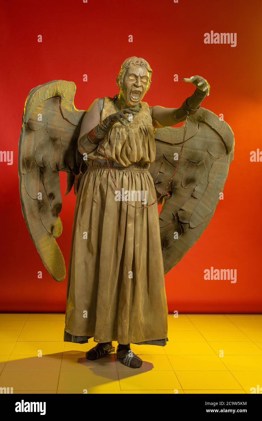 Actrice femme dans le masque et le costume de personnage de fantaisie de fiction pose sur fond rouge Banque D'Images