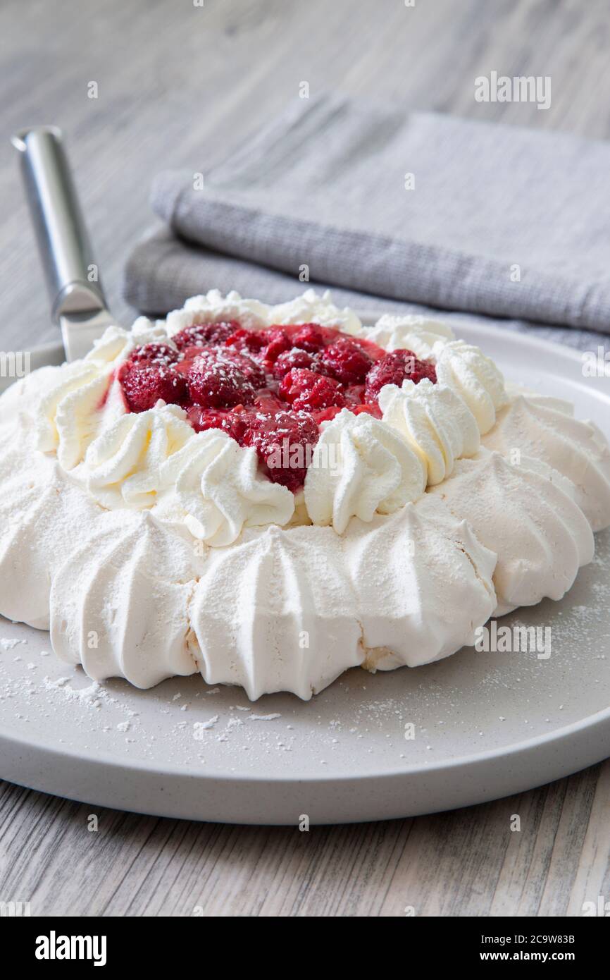 pavlova à la framboise avec trancheuse à gâteaux sur une assiette grise. Fond en bois gris Banque D'Images