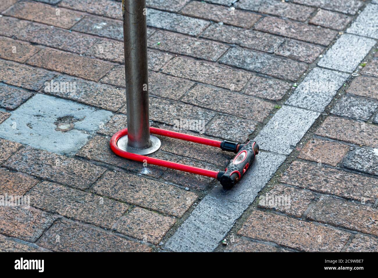 Une serrure à vélo à verrouillage en D verrouillée autour d'un poteau dans la rue Banque D'Images