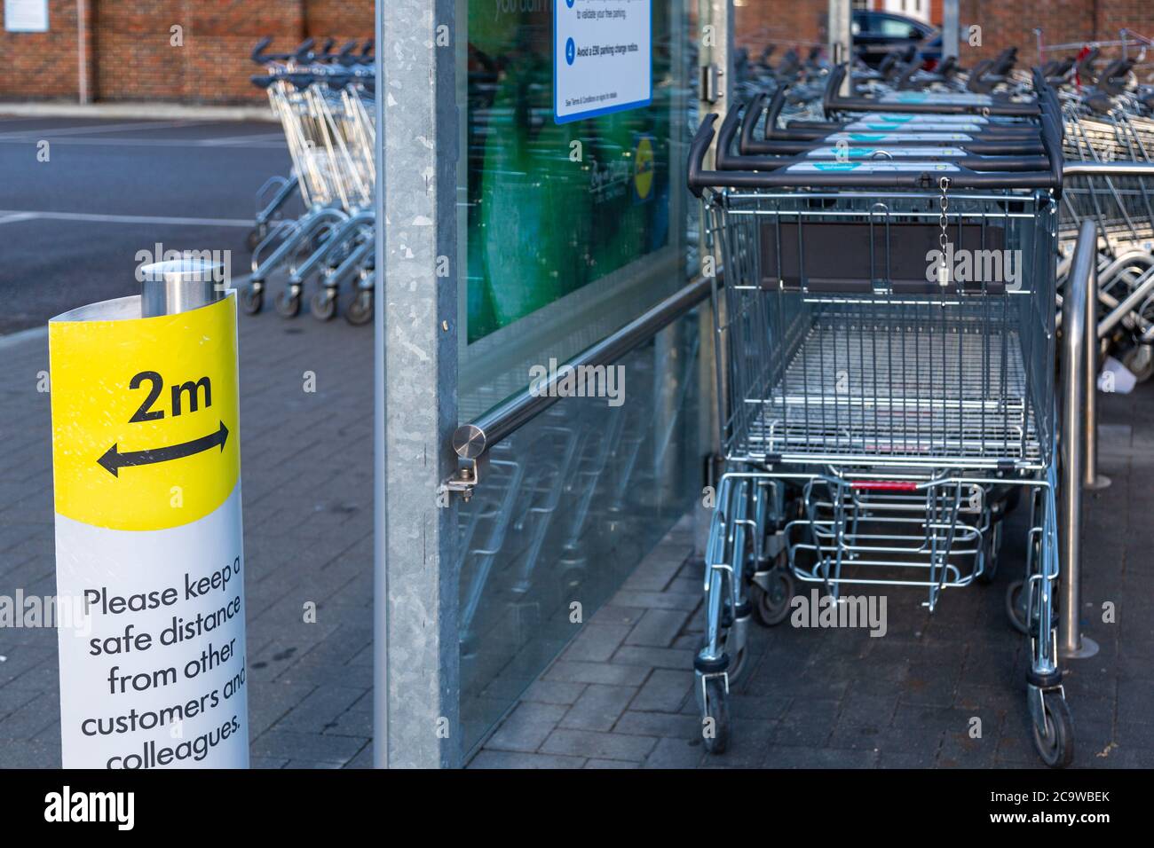 Un panneau de distance de deux mètres à côté des chariots dans un parc de trolleybus de supermarché pendant l'épidémie de coronavirus Banque D'Images