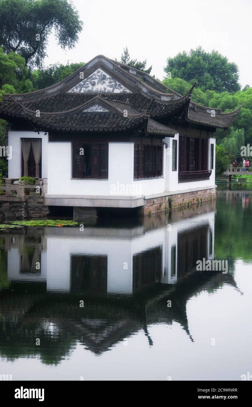 Un bâtiment chinois traditionnel surplombant un étang dans les jardins Guyi de Shanghai en Chine par une journée de grand. Banque D'Images