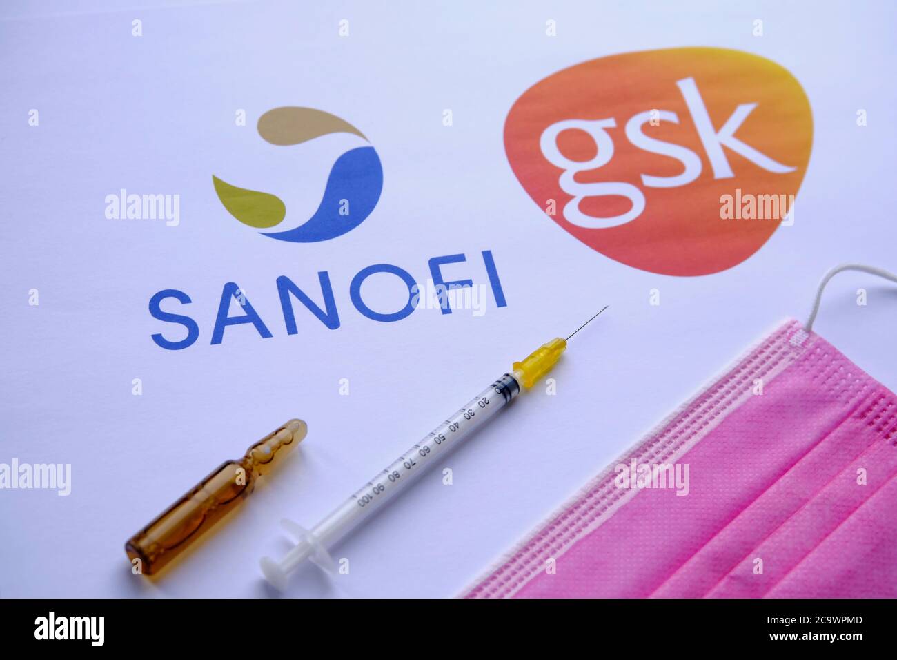 Stone / UK - 2 août 2020 : LOGOS SANOFI GSK sur fond flou et seringue avec masque viral à l'avant. Concept pour le vaccin COVID-19. Sélectif f Banque D'Images