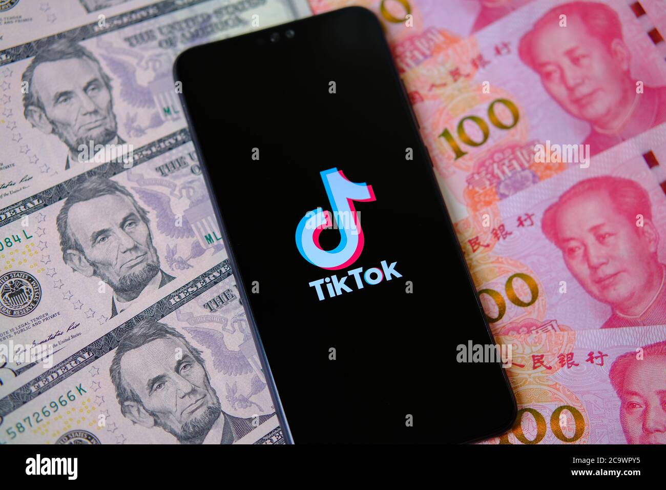 Logo de l'application TikTok à l'écran et dollars avec de l'argent yuan autour Banque D'Images