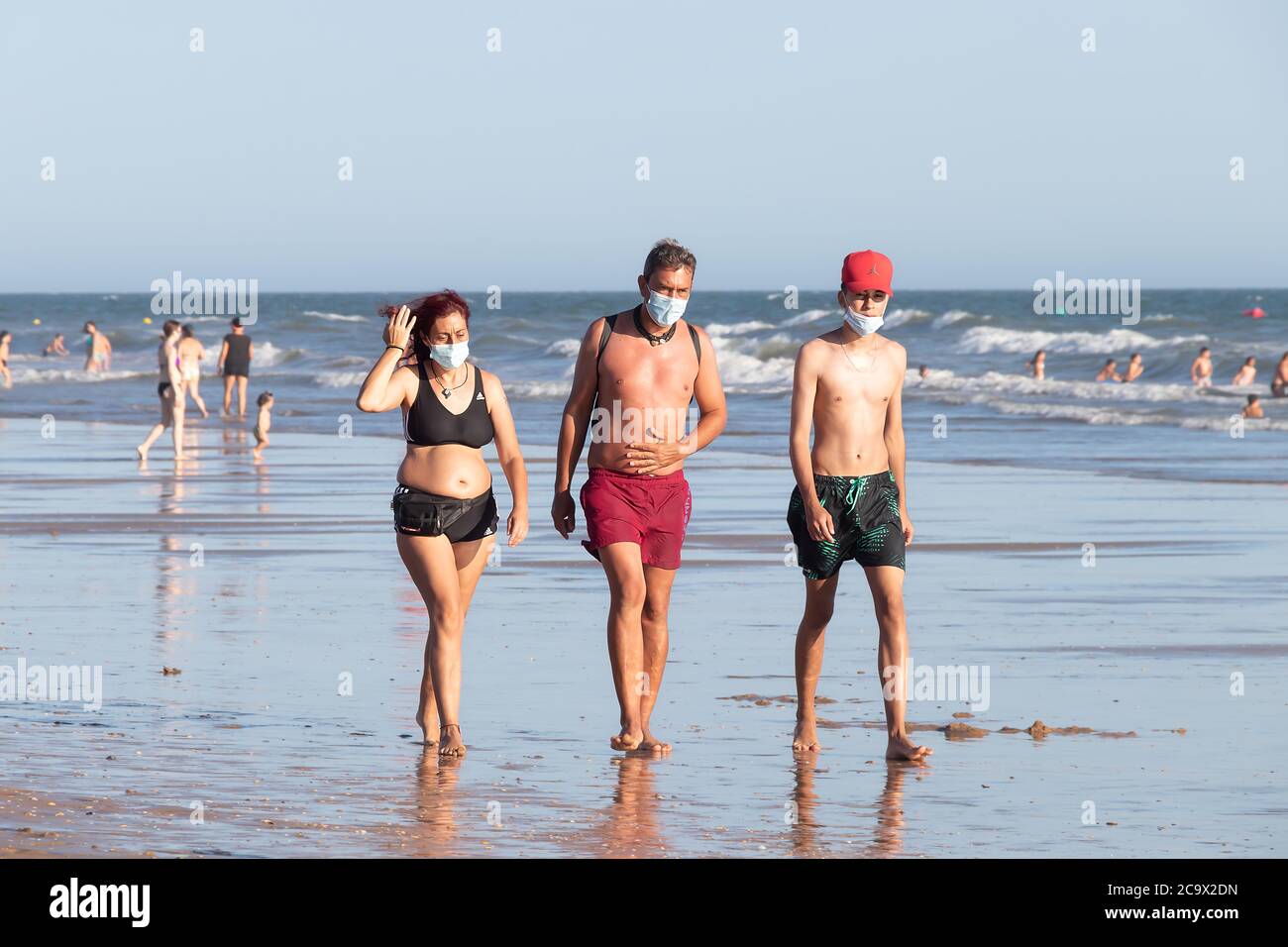 Punta Umbria, Huelva, Espagne - 2 août 2020: Personnes marchant sur la plage portant des masques protecteurs ou médicaux. Nouvelle normale en Espagne avec di social Banque D'Images