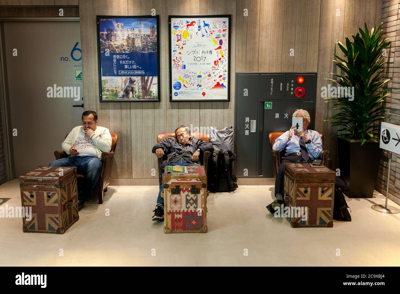 Les hommes s'assoient et utilisent des smartphones ou dorment pendant leurs achats à Hikarie Tower, Shibuya, Tokyo, Japon. Banque D'Images