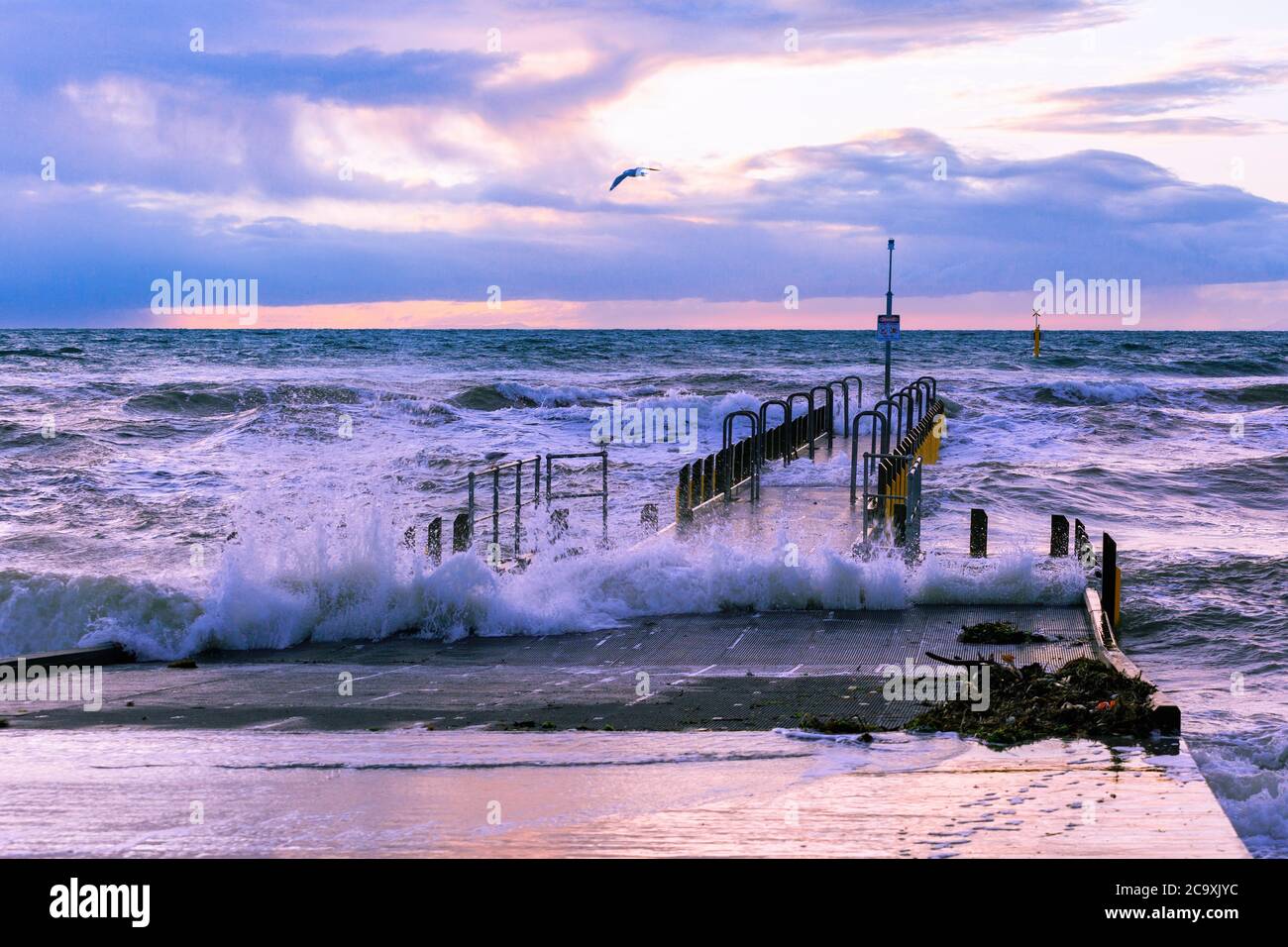 Tempête au bord de l'océan - vagues au-dessus de la jetée du bateau au coucher du soleil Banque D'Images