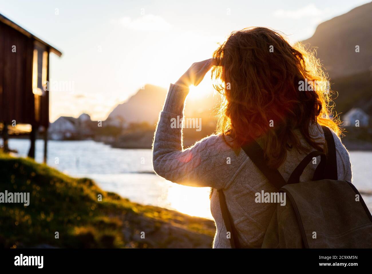 Une femme touriste avec un sac à dos regarde le coucher de soleil sur les îles Lofoten, en Norvège Banque D'Images