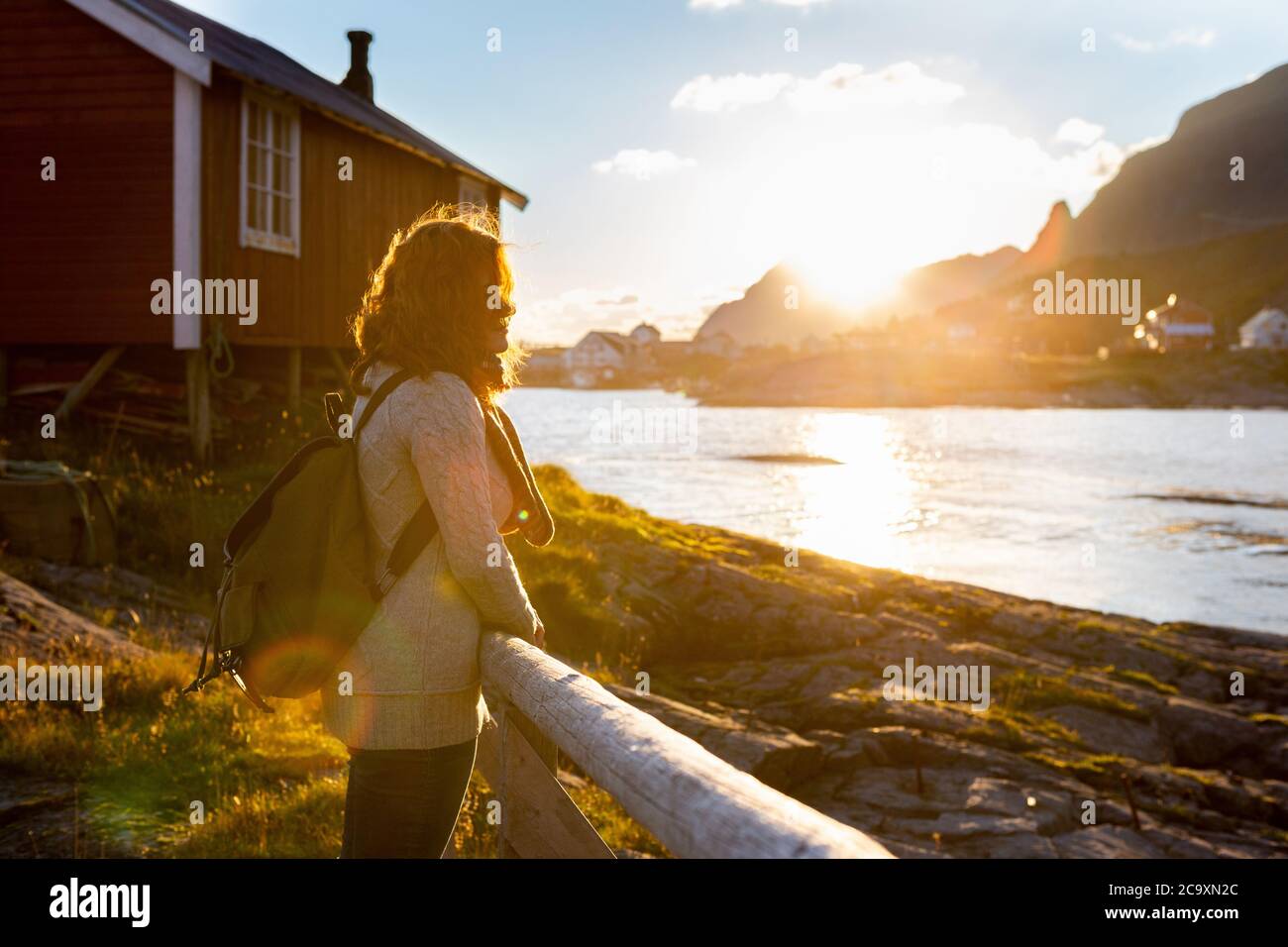 Une femme touriste avec un sac à dos regarde le coucher de soleil sur les îles Lofoten, en Norvège Banque D'Images