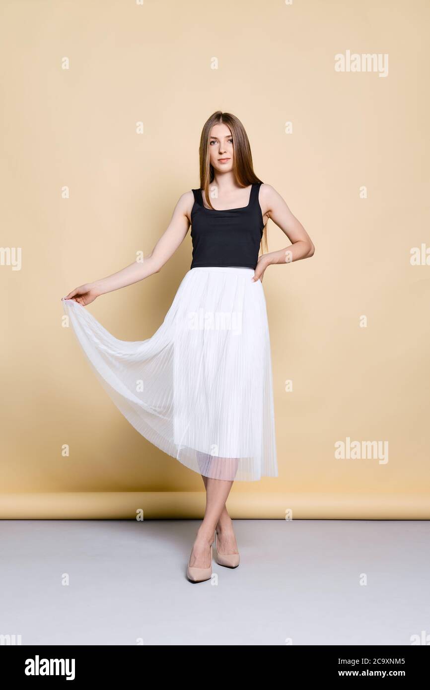 Portrait pleine longueur de jolie jeune femme en noir débardeur haut de  levage de la jupe blanche Photo Stock - Alamy