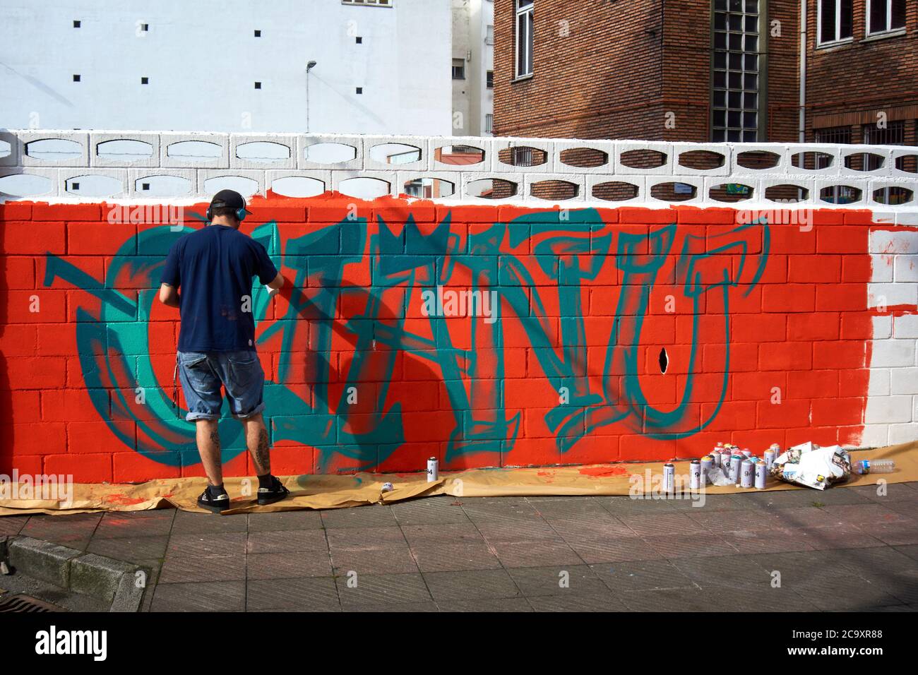 Artiste de rue peignant un graffiti coloré sur un mur blanc Banque D'Images