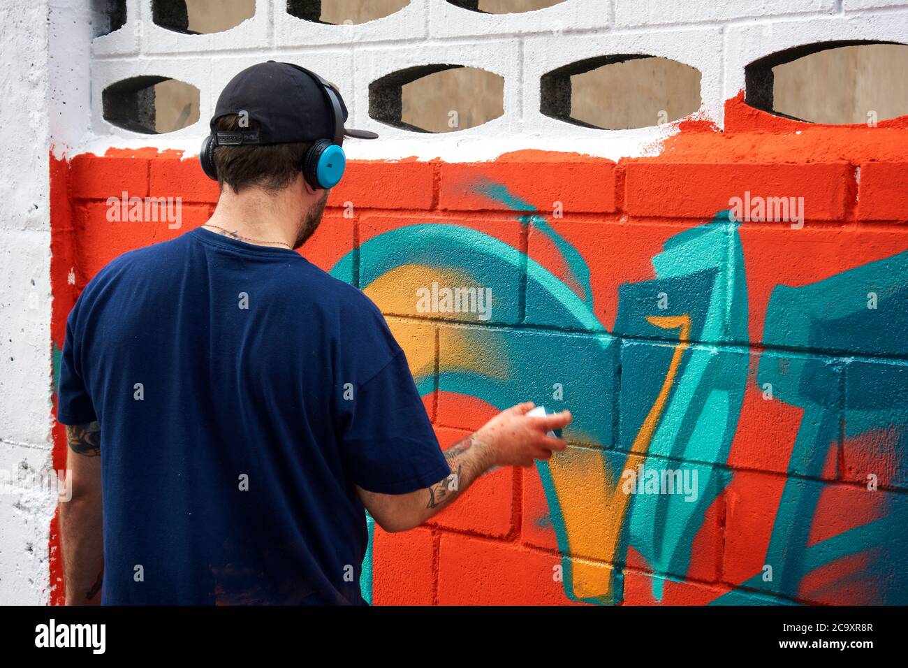 Artiste de rue peignant un graffiti coloré sur un mur blanc Banque D'Images