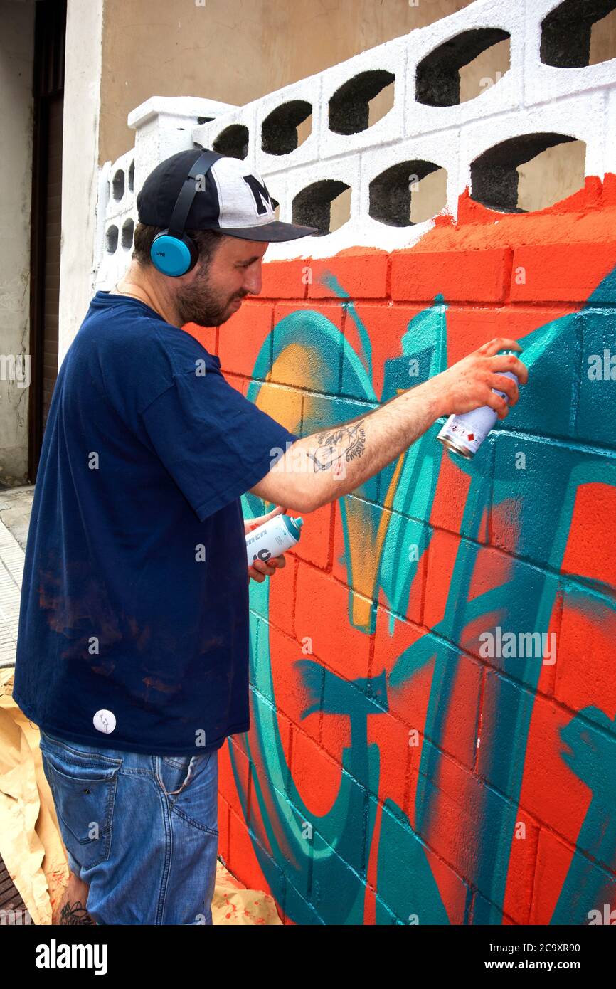 Artiste de rue peignant un graffiti coloré sur un mur blanc Banque D'Images