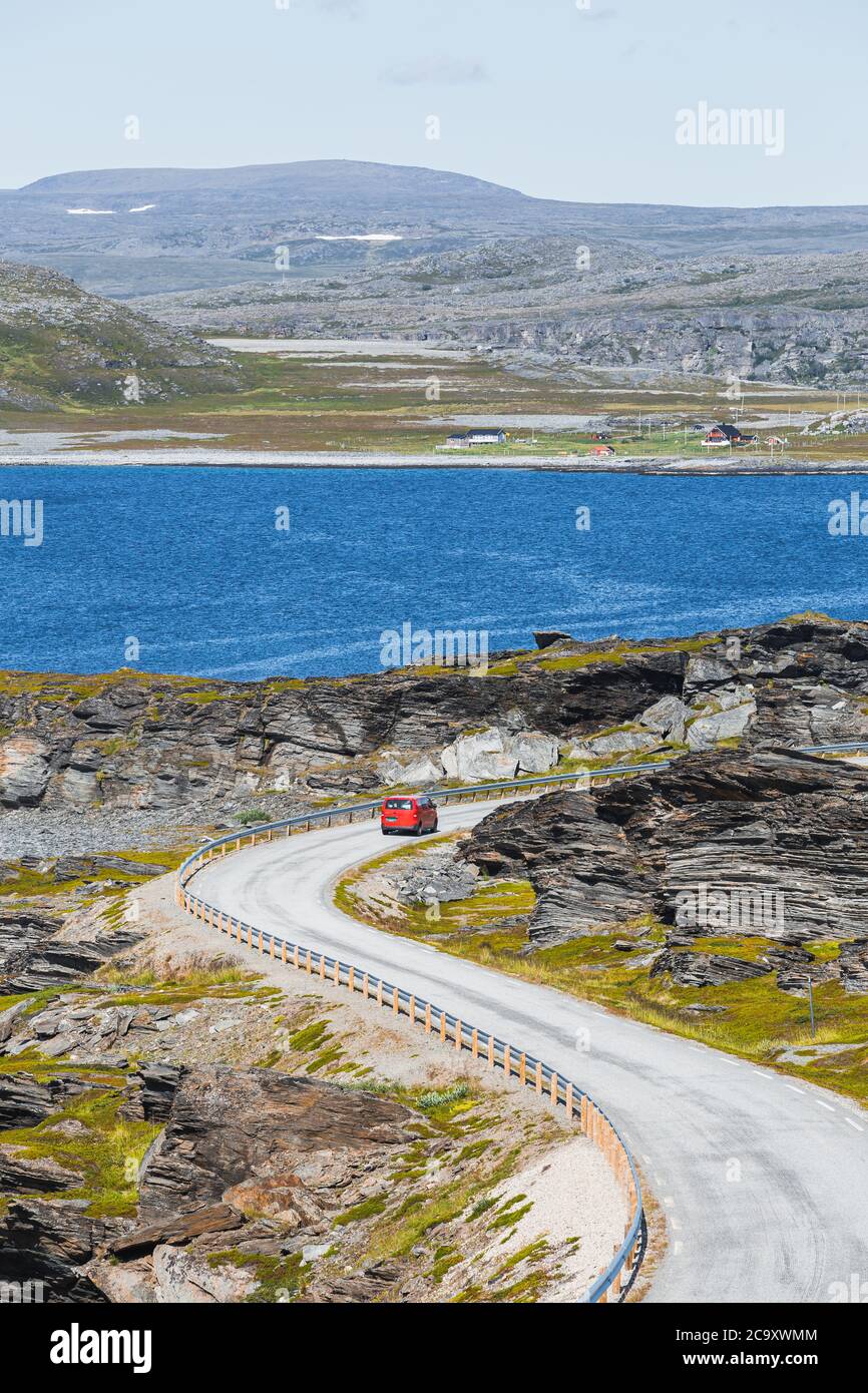 Un camion de livraison de colis rouge sur une route sinueuse dans le nord de la Norvège en été Banque D'Images