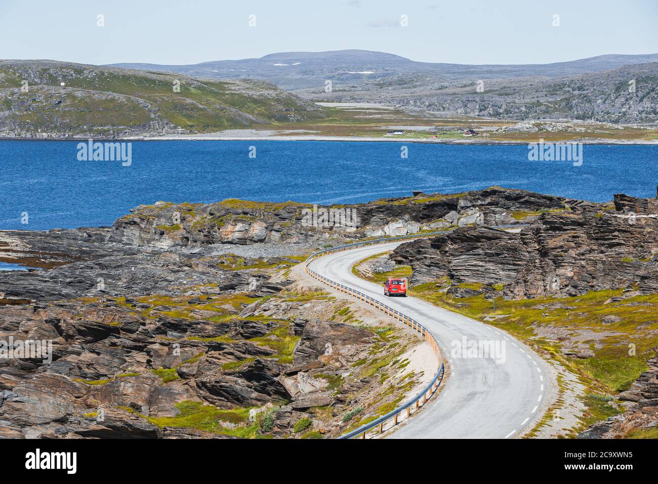 Un camion de livraison de colis rouge sur une route sinueuse dans le nord de la Norvège en été Banque D'Images