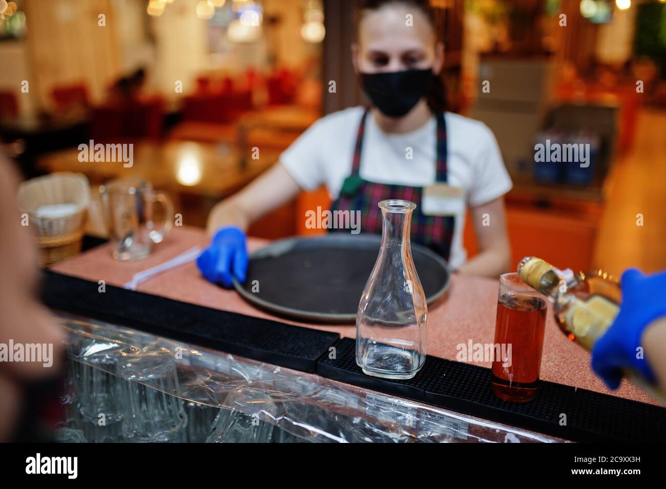 Garçon dans le masque de protection tenir le plateau avec la boisson  alcoolisée dans le restaurant Photo Stock - Alamy