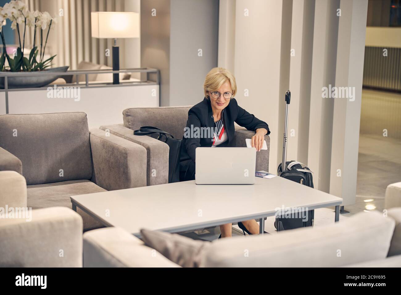 Femme charmante utilisant un ordinateur portable avant un voyage d'affaires Banque D'Images