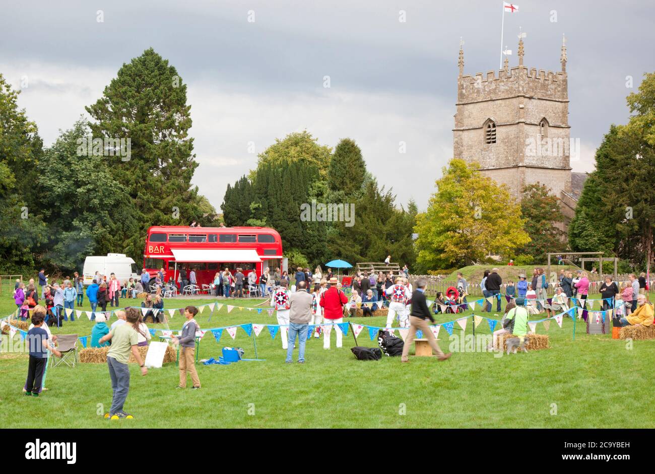 Un village des Cotswolds avec des danseuses Morris sur le terrain de jeu local Banque D'Images