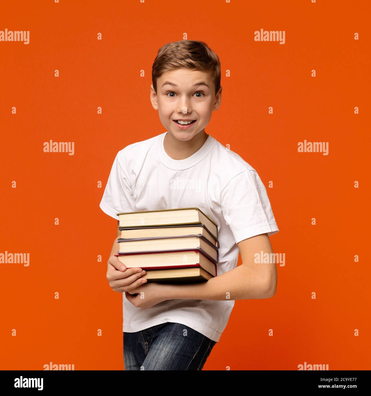 Jeune garçon souriant avec tas de livres dans les mains Banque D'Images