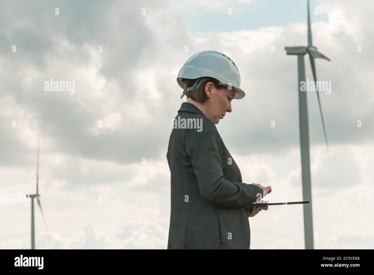 Femme ingénieur avec tablette informatique sur une ferme d'éoliennes moderne pendant la planification de projet d'entretien Banque D'Images