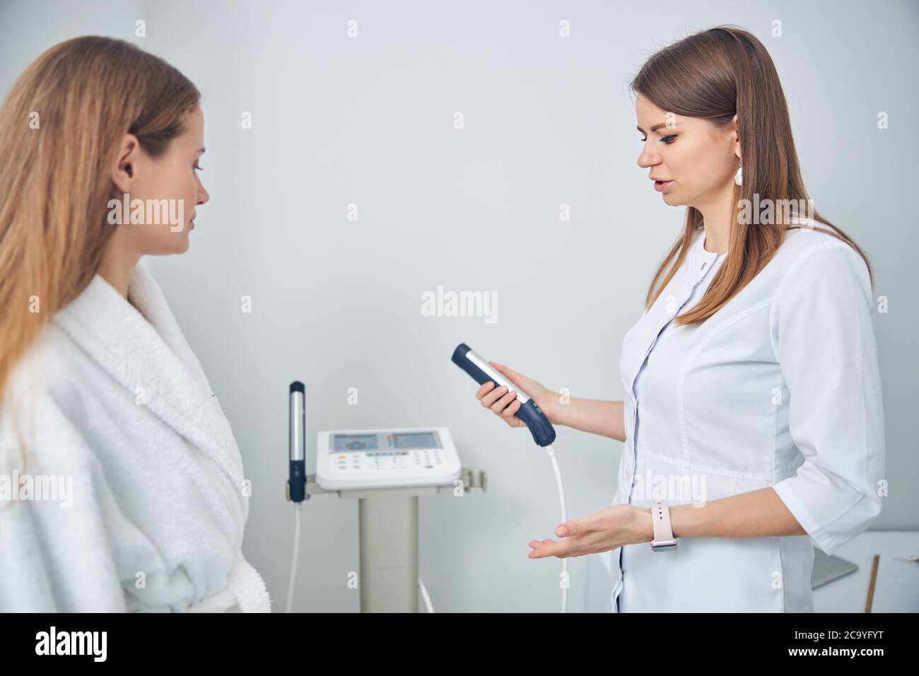 Deux belles femmes parlant de soins en utilisant la machine de médecine Banque D'Images