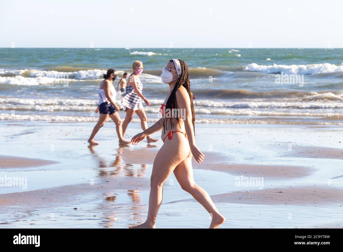 Punta Umbria, Huelva, Espagne - 2 août 2020 : jeune femme marchant sur la plage et portant des masques protecteurs ou médicaux. Nouvelle normale en Espagne avec soci Banque D'Images