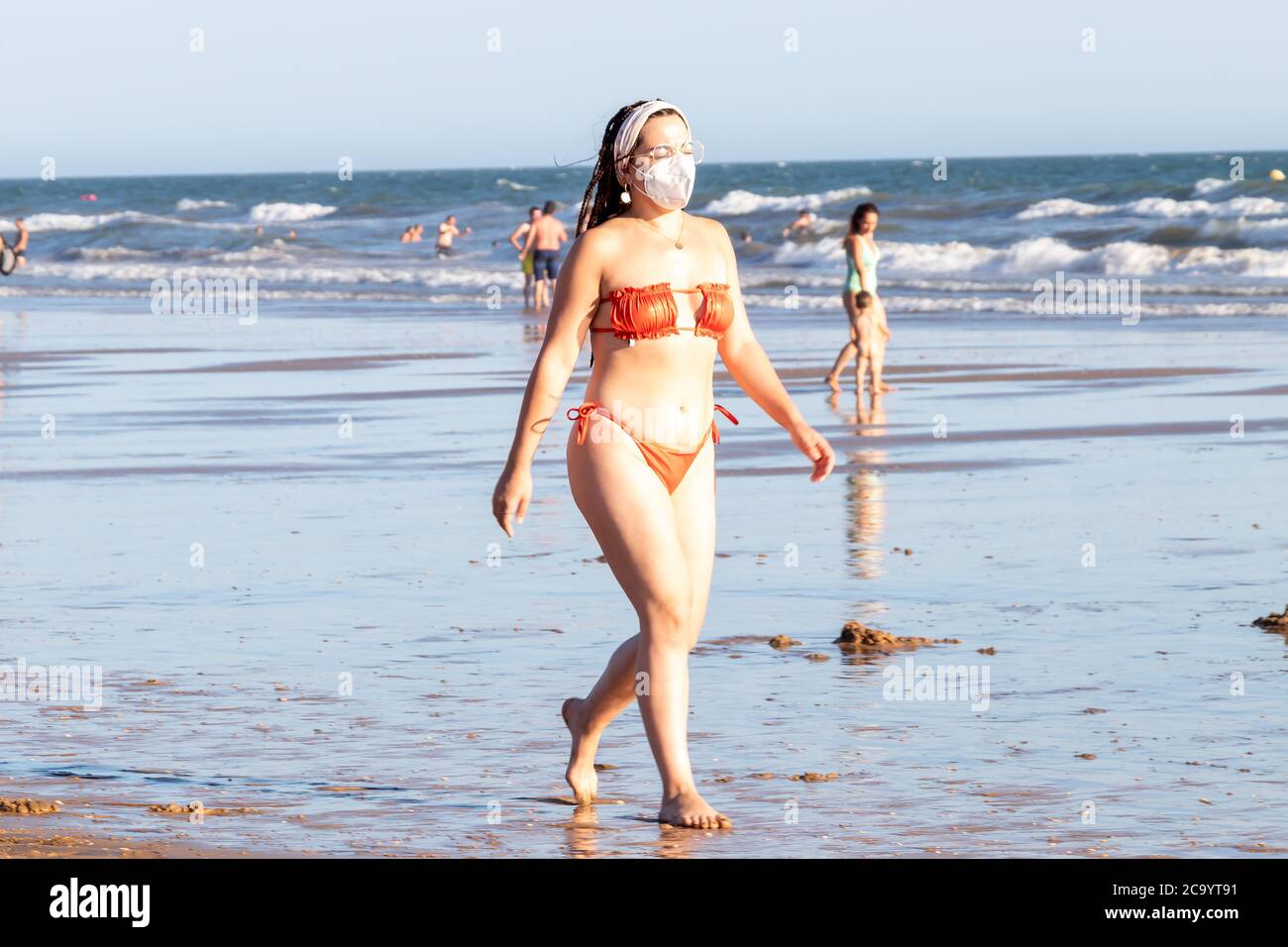 Punta Umbria, Huelva, Espagne - 2 août 2020 : jeune femme marchant sur la plage et portant des masques protecteurs ou médicaux. Nouvelle normale en Espagne avec soci Banque D'Images